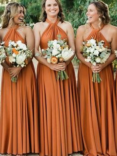 bridesmaids in orange dresses laughing and holding their bouquets at the same time