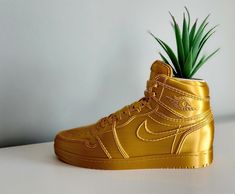 a gold nike air force high top sneaker with a green plant in the bottom