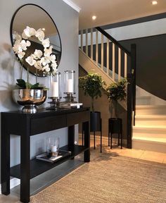 a table with flowers and candles on it in front of a staircase area that has stairs leading up to the second floor