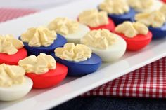 deviled eggs with mayonnaise in them on a white plate next to a red and blue checkered table cloth