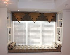 a window seat in the corner of a white room with black and white checkered flooring