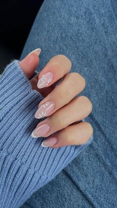 a woman's hand with pink and white manies on her nails, sitting in a blue sweater