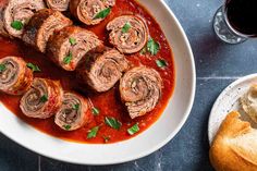 a plate of meatballs and bread on a table next to a glass of wine