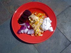 a red plate filled with food on top of a stone floor