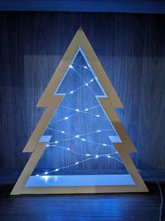 a lighted wooden christmas tree with blue lights in the shape of a triangle on a dark wood floor