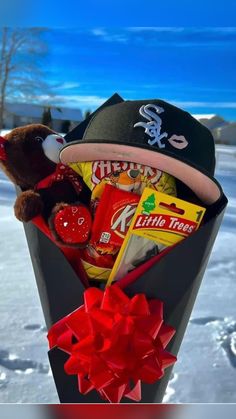 a teddy bear in a baseball cap and some candy on top of a pole with a red bow