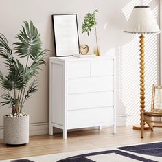 a white chest of drawers next to a lamp and potted plant in a living room