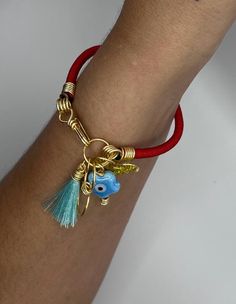 a close up of a person wearing a red bracelet with gold charms and tassels