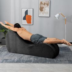 a man laying on top of a black bean bag chair in a living room next to a lamp