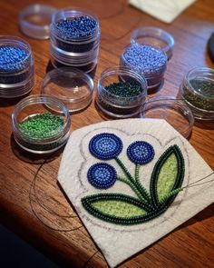 some beads are sitting on a table next to glass bowls and a cloth with flowers in them