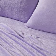 a bed covered in purple sheets and pillows