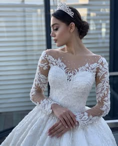 a woman wearing a wedding dress with long sleeves and a tiara on her head