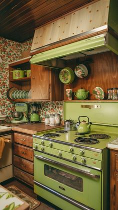 a green stove top oven sitting inside of a kitchen next to wooden cabinets and drawers