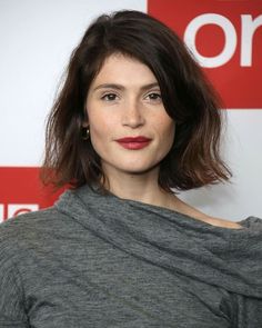 a close up of a person wearing a gray shirt and red lipstick on her lips