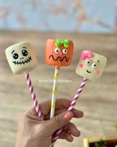 three marshmallows with faces and candy sticks