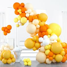 an arrangement of balloons floating in the air next to a vase and busturine