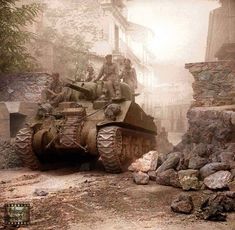 two men are sitting on top of a tank in the middle of a dirt road