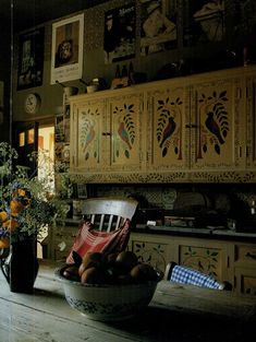 a bowl full of fruit sitting on top of a wooden table next to a vase filled with flowers