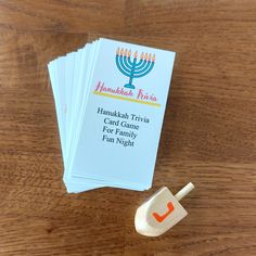 four hanukkah trivia cards on a wooden table next to a toy menorah