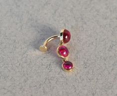 a pair of gold and pink stone earrings on top of a white surface with small dots