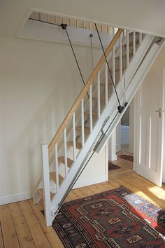 a stair case in an empty room with wood flooring and rugs on the ground