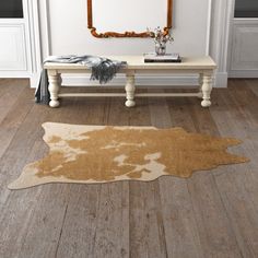 a brown and white cowhide rug on a wooden floor in front of a mirror