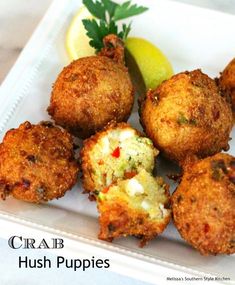 some fried food on a white plate with lemon wedges