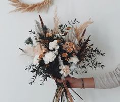 a woman holding a bouquet of flowers in her hand with wheat stalks on the side