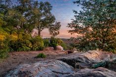 the sun is setting over some rocks and trees