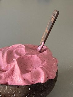 a bowl filled with pink frosting sitting on top of a table next to a knife