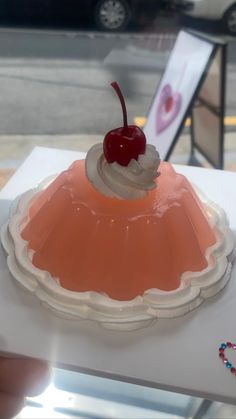 a cherry topped dessert sitting on top of a white table