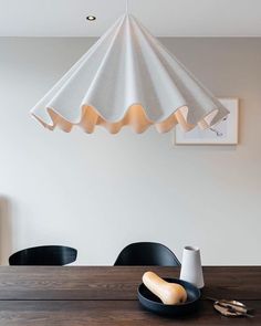 a dining room table with two black plates on it and a white lamp hanging from the ceiling