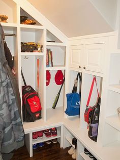 a white closet filled with lots of sports gear and bags next to a coat rack