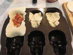 three skull shaped pans filled with food on top of a counter