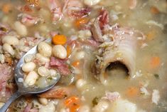 a spoon full of soup with meat, beans and carrots