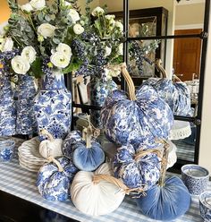 several blue and white pumpkins are sitting on a table with flowers in vases