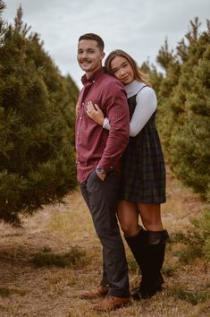 a man and woman are hugging in the middle of a tree farm, surrounded by pine trees