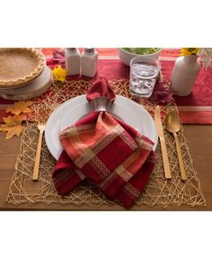 a place setting with red and gold napkins, silverware, and pumpkins