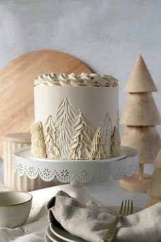 a white cake sitting on top of a table next to plates and silverware with trees in the background