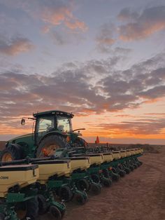 a tractor is parked in the middle of a field with two rows of tractors behind it