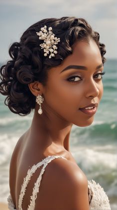 a woman in a wedding dress standing on the beach with her hair pulled back and wearing an intricate head piece