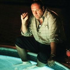 a man sitting on top of a swimming pool next to a glass filled with liquid