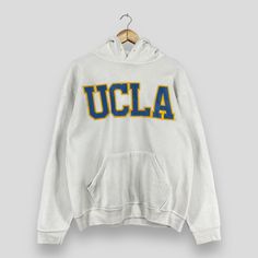 "REMINDER: THIS IS USED CLOTHING PLEASE DO NOT EXPECTED IT LIKE TO BE NEW OR IN PRISTINE CONDITION Feel free to contact me for any question. I'll assist you with my pleasure. Vintage UCLA Pullover Hoodie Large 1990's University Of California Spellout Embroidery Sportswear Sweater Ucla White Hoodie Sweater Size L *All measurements are taken with the garment flat on the ground. SIZE ON TAG :- Size L ACTUAL SIZE MEASUREMENT :- ARM PIT TO ARM PIT :- 23\" inches BACK COLLAR TO HEM :- 26\" inches CONDITION :- GREAT USED CONDITION. NO HOLES AND STAINS. ** WE ARE USING DHL EXPRESS, IT TAKES 3-5 WORKING DAYS ONLY TO ARRIVE. PLEASE LEAVE YOUR PHONE NUMBER ON THE NOTE WHILE MAKE A PURCHASE** REF : (13-01-2021) 888" Varsity Hoodie With Drawstring Hood For College, Collegiate White Sweatshirt With Drawstring Hood, White Collegiate Sweatshirt With Drawstring Hood, Vintage Hoodie With Double-lined Hood For Sports, Collegiate Cotton Hoodie For Campus, Retro College Hoodie With Drawstring Hood, White Sporty Hoodie With Letter Embroidery, Sporty White Hoodie With Letter Embroidery, Retro Fall Sports Hoodie