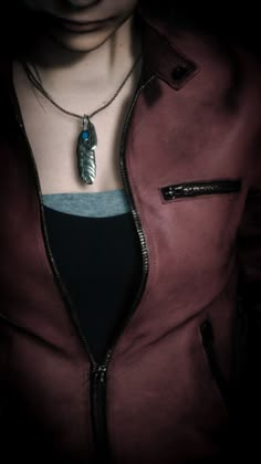 a close up of a person wearing a necklace with a feather on it's back