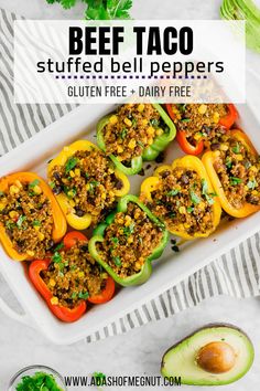 stuffed bell peppers in a baking dish with avocado on the side