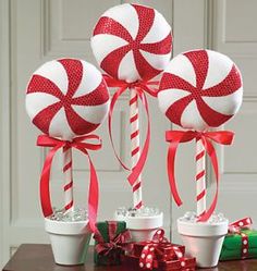 three lollipops with red and white stripes on them, tied in ribbon