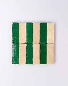 four pieces of green and white striped tile on a white surface with one piece missing