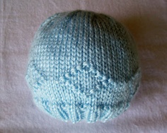 a blue knitted hat sitting on top of a white sheet