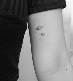 a woman's arm with two saturn tattoos on the left side of her arm