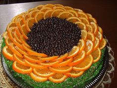 a cake decorated with oranges and black seeds on a tablecloth covered plate,